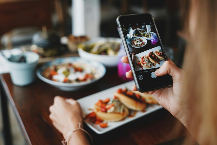 crop woman taking shot of food on mobile phone during lunch