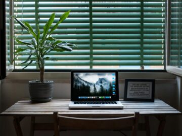 photo of macbook air on a table next to house plant and picture frame