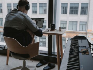 man in gray shirt sitting on chair in front of computer