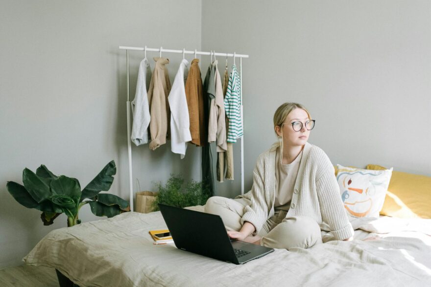 a woman in beige sweater sitting on the bed