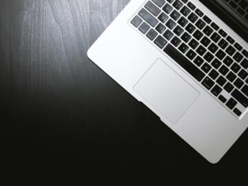 Top view of a sleek laptop on a dark wooden desk, showcasing modern technology.