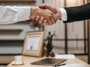 Close-up of a handshake between two professionals in a modern office setting, emphasizing partnership and agreement.